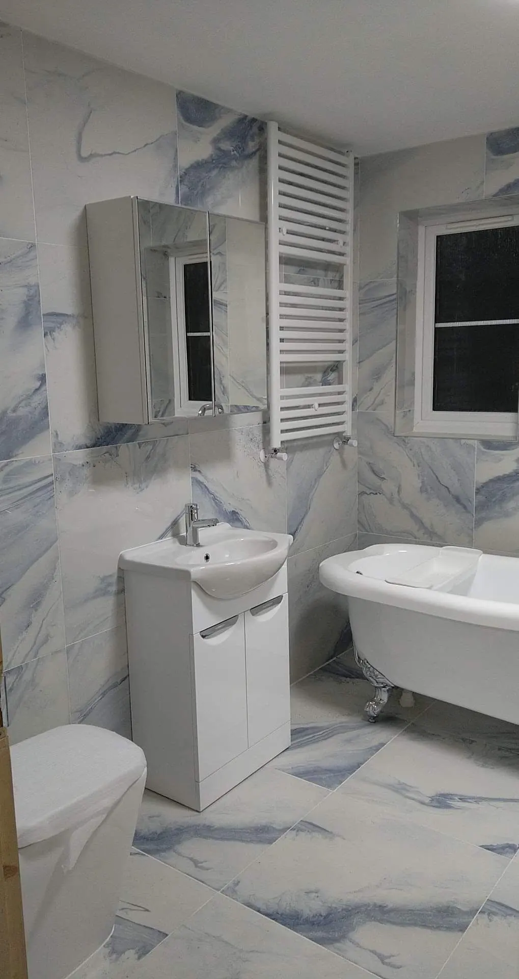 Bathroom with blue-veined marble-effect tiles, towel radiator and freestanding bath
