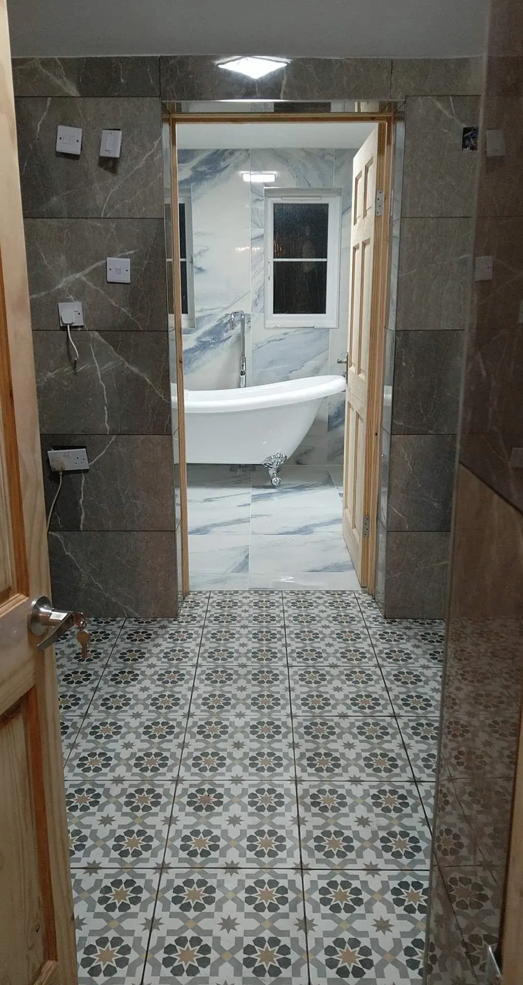Doorway view into a tiled bathroom with a freestanding bath