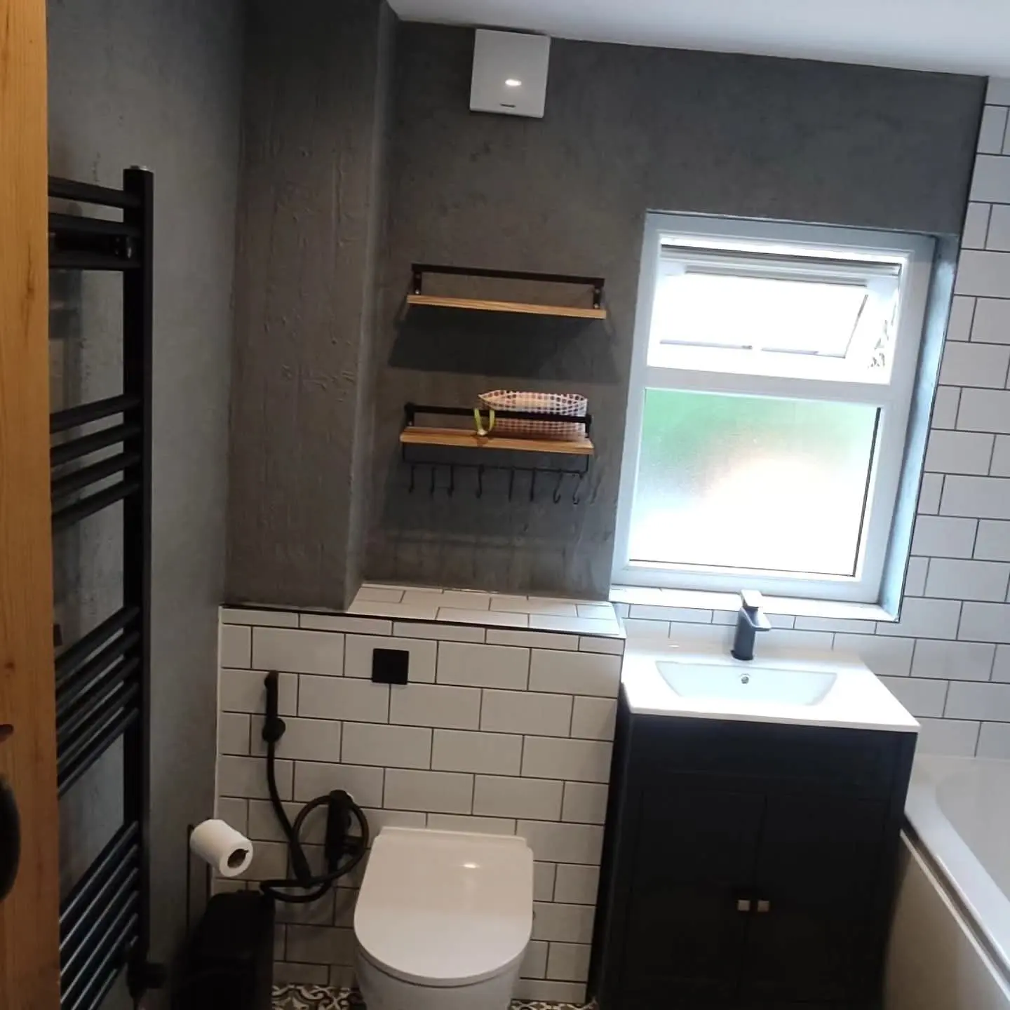 Bathroom with white metro tiles, a black vanity and a black towel radiator