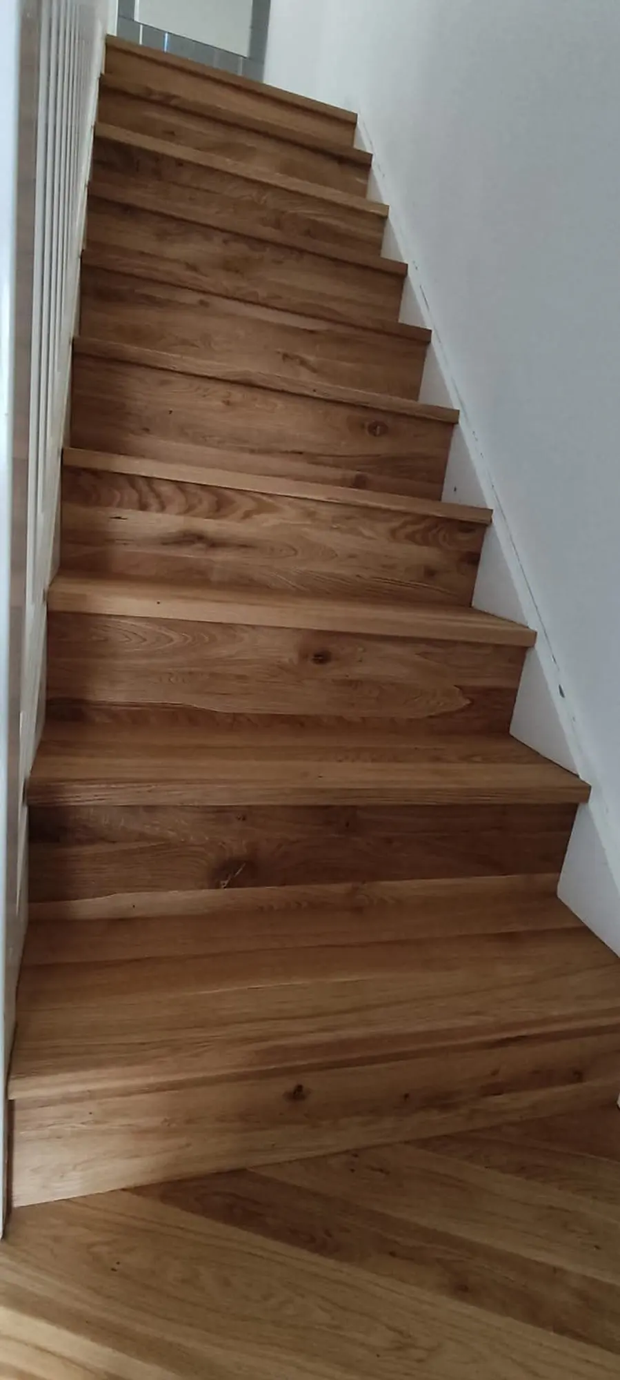 Straight staircase clad in oak treads and risers, seen from the bottom