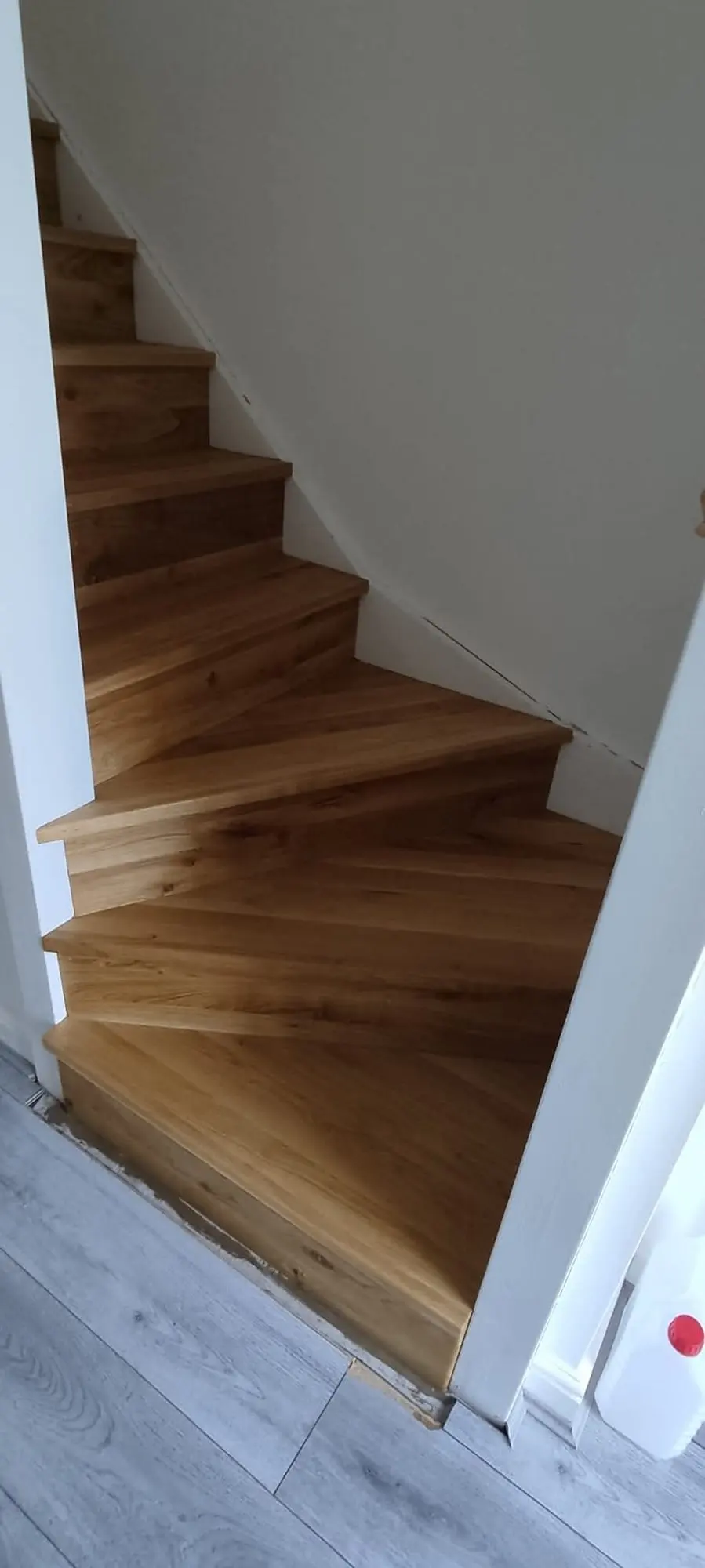 Narrow staircase clad in oak treads and risers with a turn at the bottom