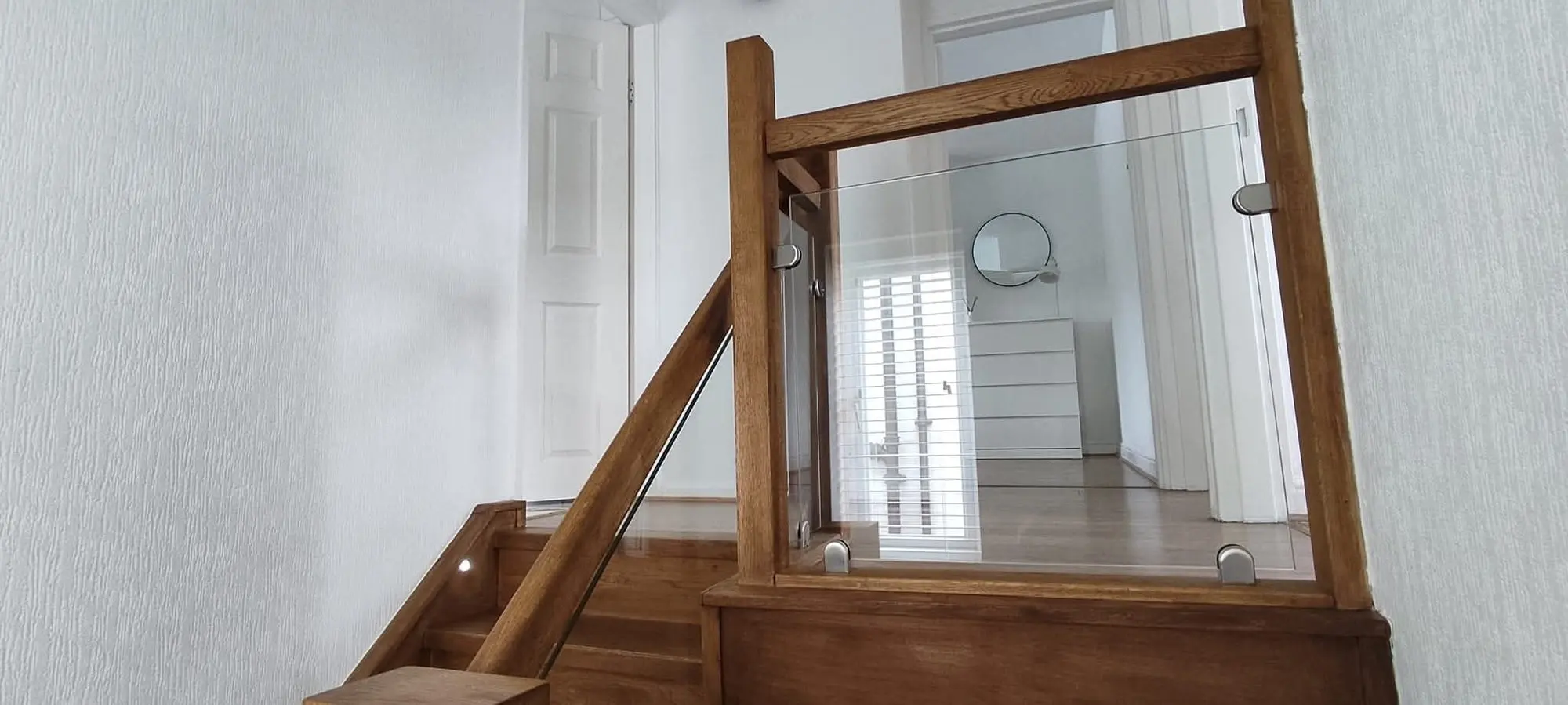 Oak landing balustrade with glass panels and a timber handrail