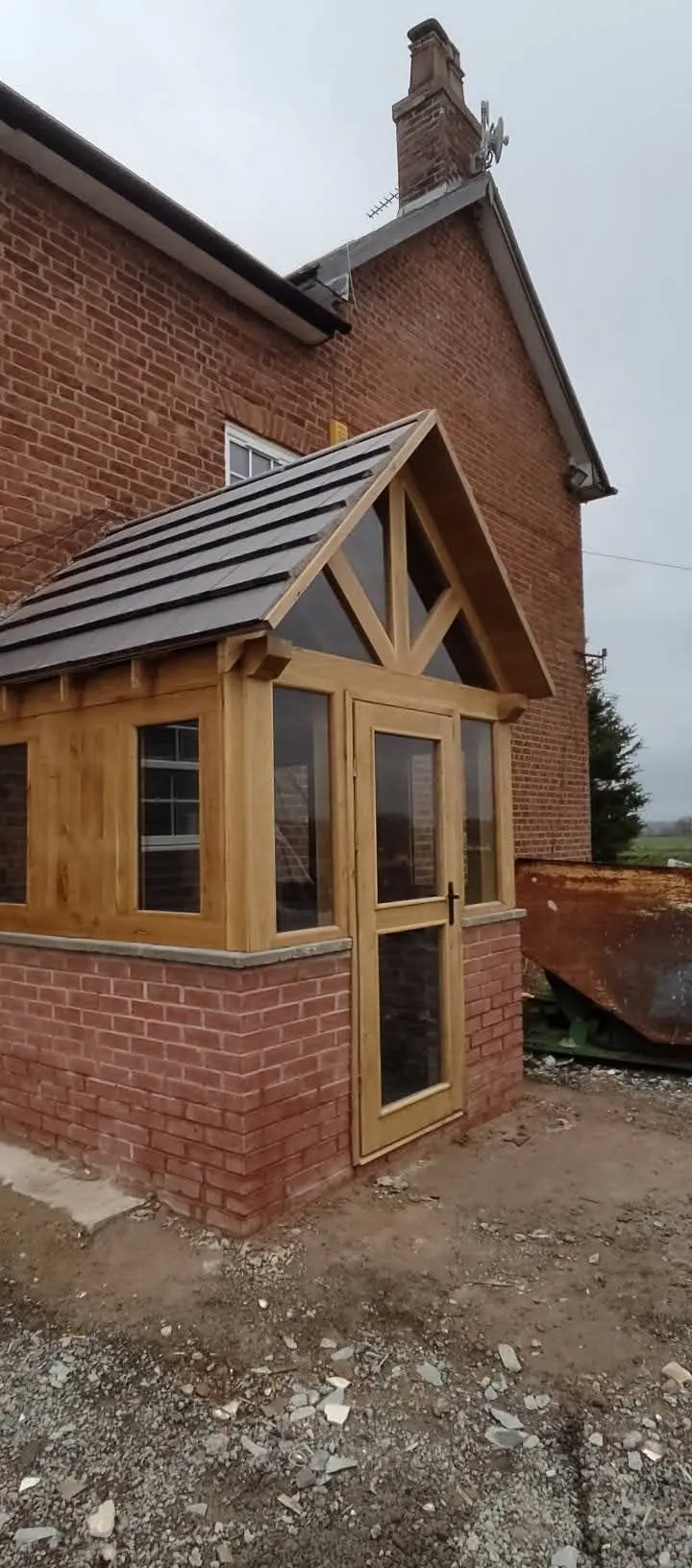 Oak-framed glazed porch on a brick base, before landscaping