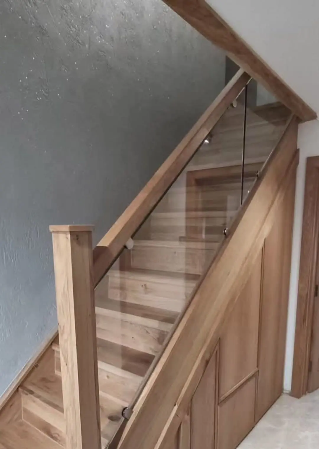 Oak staircase with a glass balustrade, oak handrail and panelled understairs