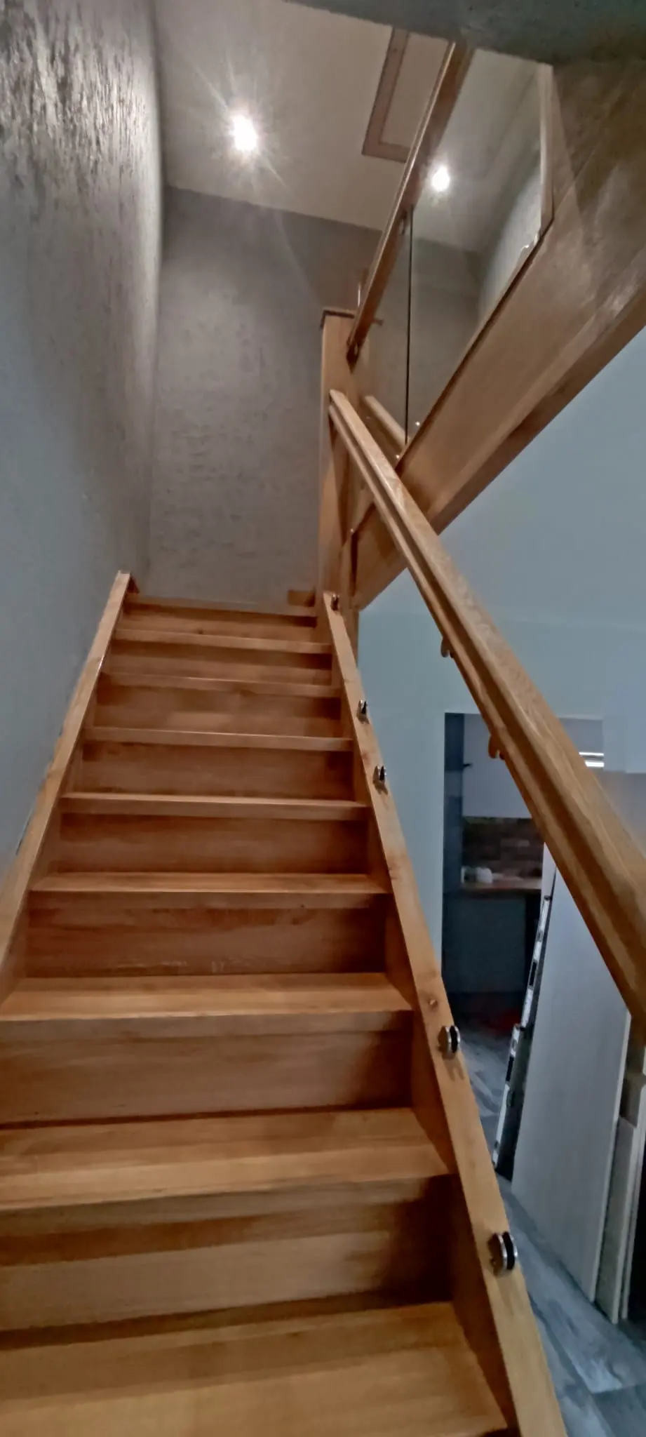Timber staircase with a turn at the top, a glass panel and a timber handrail